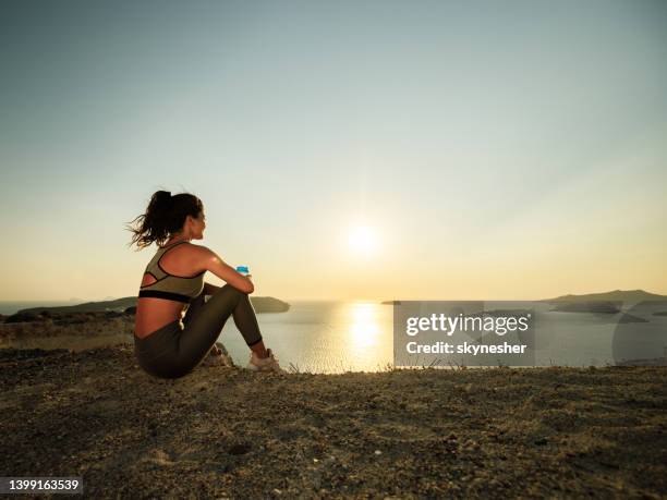 female athlete taking a water break on a hill above the sea. - groyne bildbanksfoton och bilder