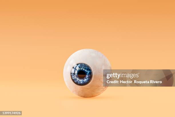 computer generated image of human eye with blue pupil in orange background, 3d render - bulbo oculare foto e immagini stock