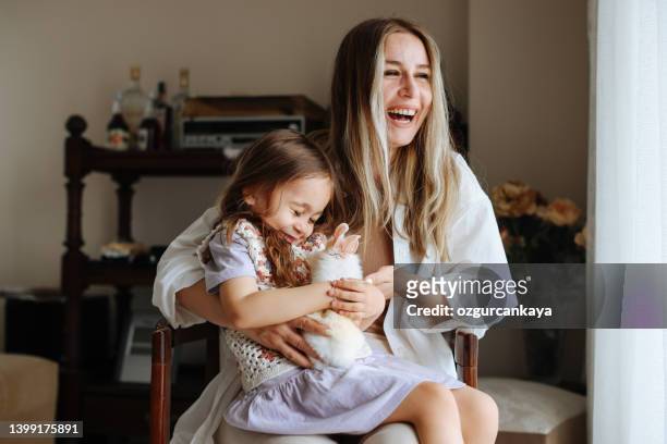 young mother and cute little girl with white rabbit - family rabbit stock pictures, royalty-free photos & images