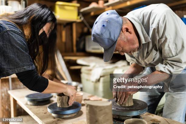 年配の男性が自分のスタジオで女性に陶芸を教える - 工芸品 ストックフォトと画像