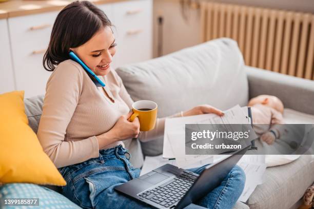 young mother checking her finances while her baby is asleep - save our future babies stock pictures, royalty-free photos & images