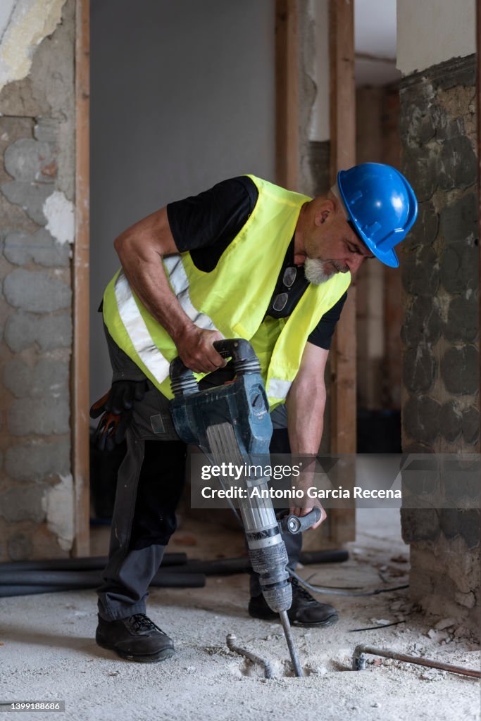 Construction worker with pneumatic hammer intended to drill the cement and concrete floors