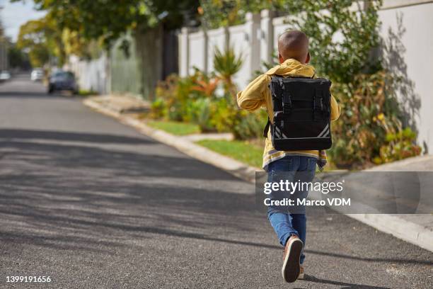 petit garçon qui court à l’école. vue arrière d’un enfant portant un cartable et se précipitant dans la rue. gestion du temps et retard - enfant cartable photos et images de collection