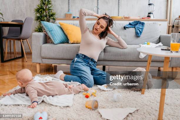 joven madre cansada con su recién nacido - kids mess carpet fotografías e imágenes de stock