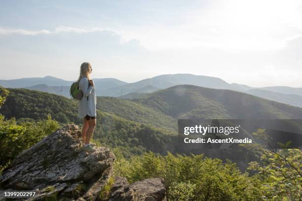 female hiker relaxes at viewpoint, at sunrise - person standing far stockfoto's en -beelden