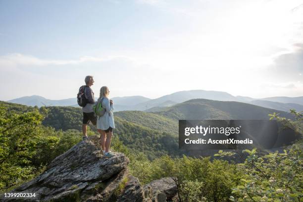 mature hiking couple relax at viewpoint - senior couple stock pictures, royalty-free photos & images
