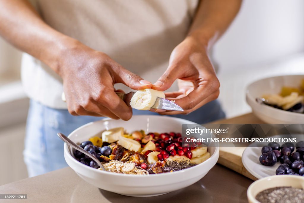 Close up of woman making healthy breakfast in kitchen with fruits and yogurt