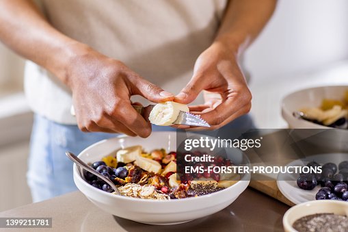 Close up of woman making healthy breakfast in kitchen with fruits and yogurt Close up of woman making healthy breakfast in kitchen with fruits and yogurt