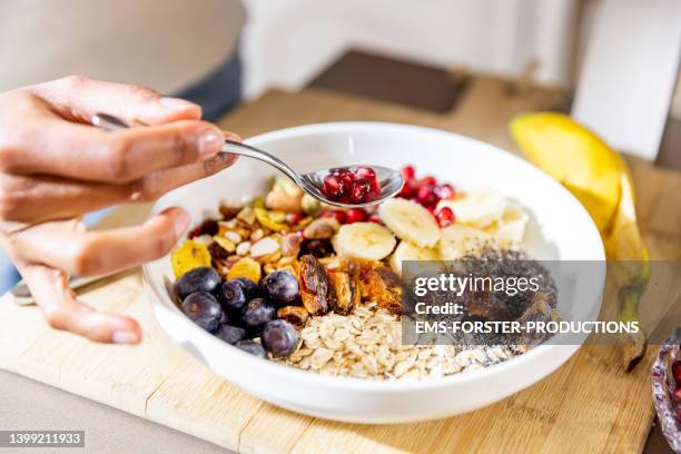 close up of a female hand eating a healthy bowl with various fruits,  berries with chia seeds and nuts - low carb diet stock pictures, royalty-free photos & images