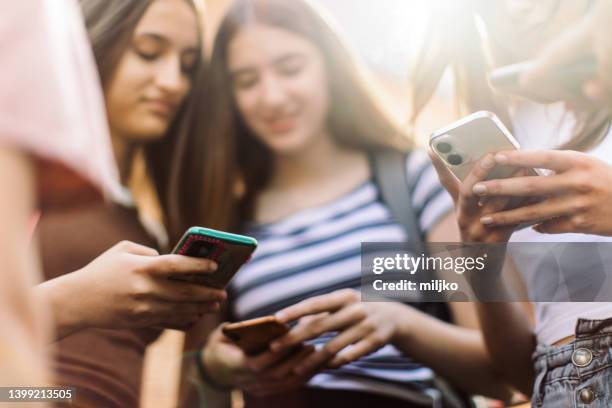 teenage girls have fun and conversation using their mobile phones - girl school bildbanksfoton och bilder