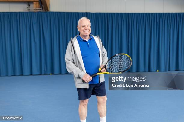 portrait of a smiling senior man playing tennis on the indoor court - 80s tennis players stock pictures, royalty-free photos & images
