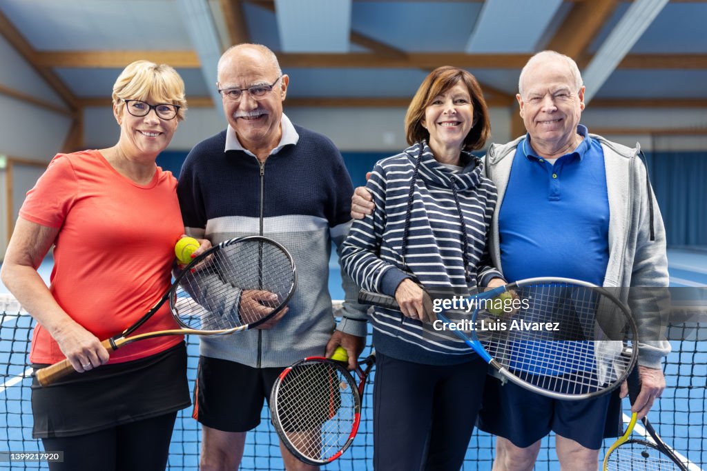 Portrait of mature couples in sportswear standing on a tennis court