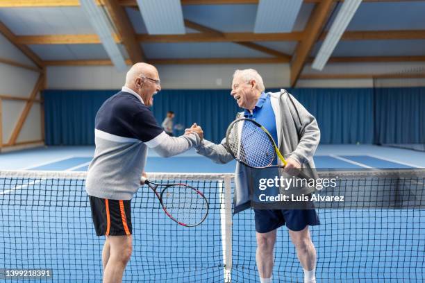 senior tennis players greeting each other after a game of tennis - abrigo azul fotografías e imágenes de stock