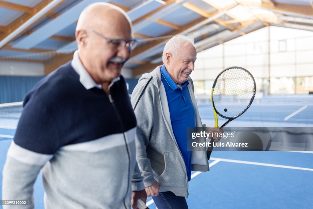 Mature men playing tennis on an indoor court