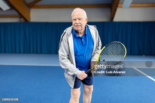 senior male in sportswear playing tennis on indoor court - 80s tennis players stock pictures, royalty-free photos & images