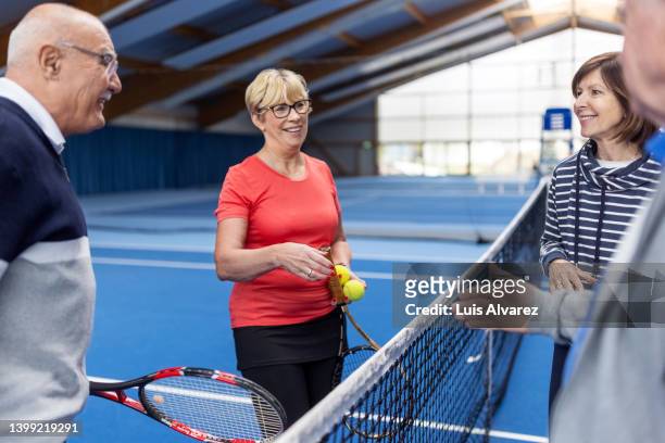 smiling senior couples exchange greetings after a game of tennis - 80s tennis players stock pictures, royalty-free photos & images