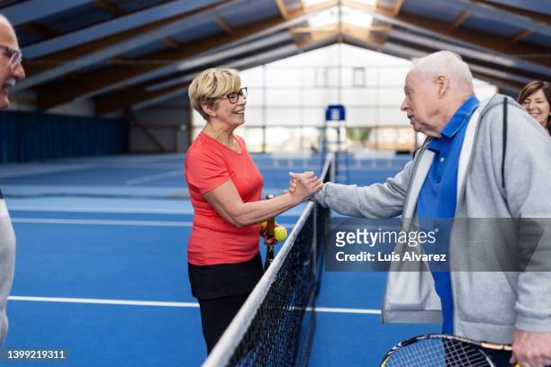 active senior couples exchange greetings after a game of tennis - 80s tennis players stock pictures, royalty-free photos & images