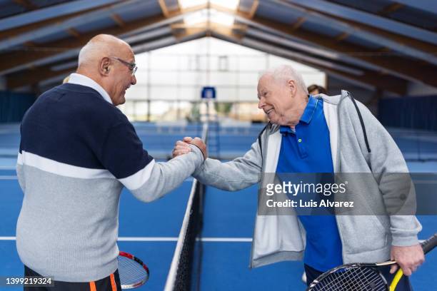 active senior men exchange a handshake after a game of tennis - 80s tennis players stock pictures, royalty-free photos & images