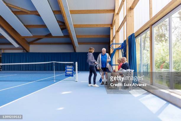 group of senior people resting after a game of tennis on indoor court - 80s tennis players stock pictures, royalty-free photos & images