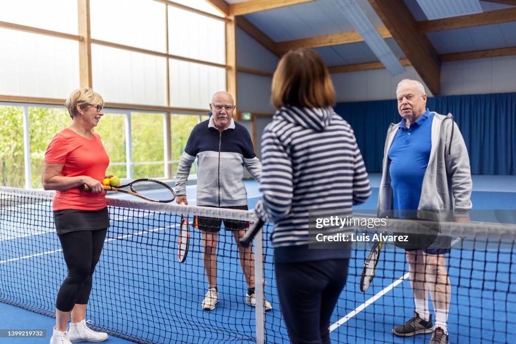 Active senior couples talking after a tennis game on the court