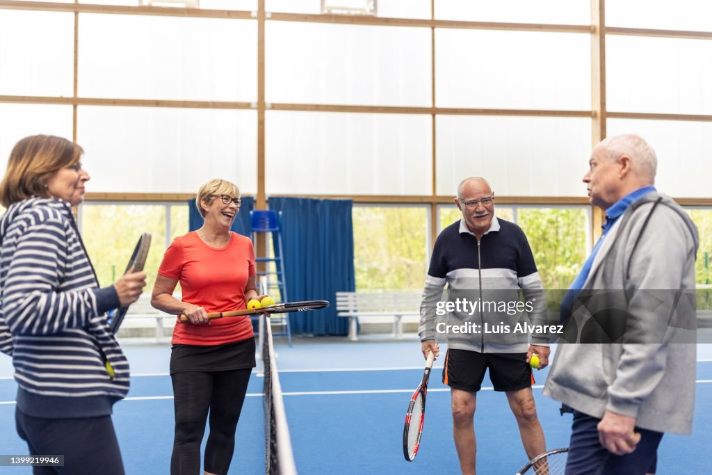 Happy senior couples playing tennis on indoor court