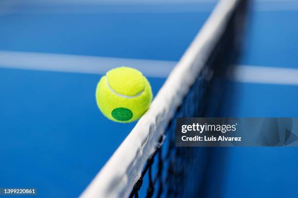 yellow tennis ball hitting the net of blue tennis court - saltar para cima e para baixo imagens e fotografias de stock