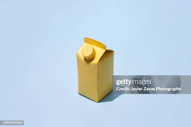 yellow small milk or juice box on blue background - yellow milk stock-fotos und bilder