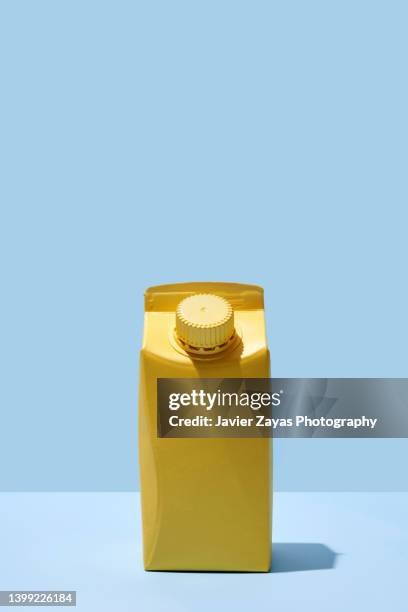 yellow small milk or juice box on blue background - juice box stock pictures, royalty-free photos & images