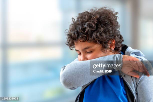 yong boy teenager sneezing into his elbow.to avoid infecting others - covering cough stock pictures, royalty-free photos & images