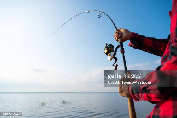 closeup man fishing in the lake - fishing rod stock-fotos und bilder