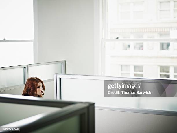businesswoman sitting in cubicle in office - guardare fisso foto e immagini stock