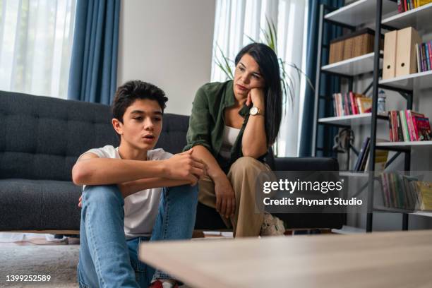 mother and son sitting after quarrel at home - stress resistant stockfoto's en -beelden