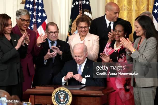 Flanked by U.S. Vice President Kamala Harris, lawmakers and cabinet members, U.S. President Joe Biden signs an executive order enacting further...