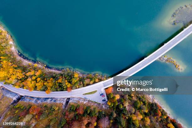 idyllic road by the lake in autumn - above clouds stock-fotos und bilder