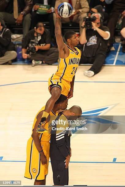 Paul George of the Indiana Pacers dunks the ball over teammates Roy Hibbert and Dahntay Jones of the Indiana Pacers during the Sprite Slam Dunk...