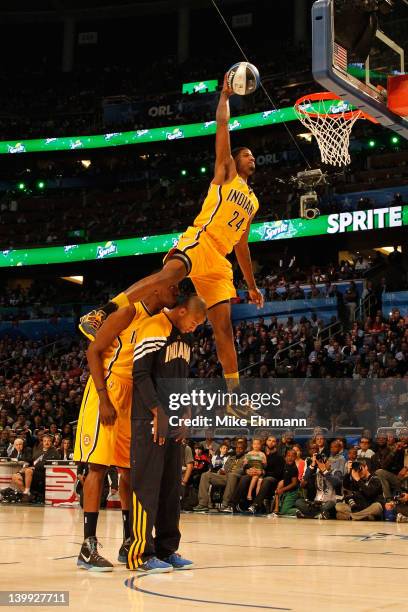 Paul George of the Indiana Pacers jumps over pacers teammates Roy Hibbert and Dahntay Jones as he dunks during the Sprite Slam Dunk Contest part of...