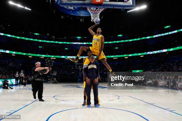 Paul George of the Indiana Pacers jumps over pacers teammates Roy Hibbert and Dahntay Jones as he dunks during the Sprite Slam Dunk Contest part of...