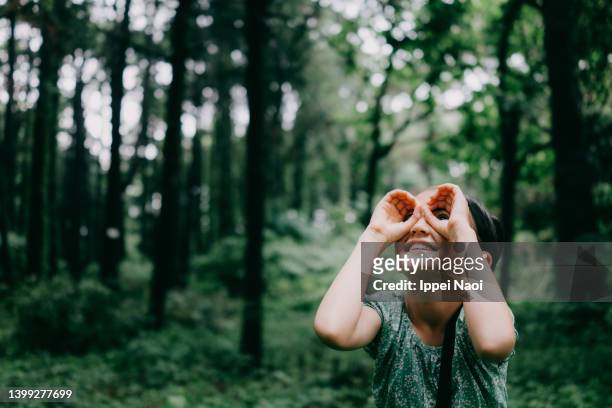 young girl pretending to look through binoculars in forest - children binocular stockfoto's en -beelden