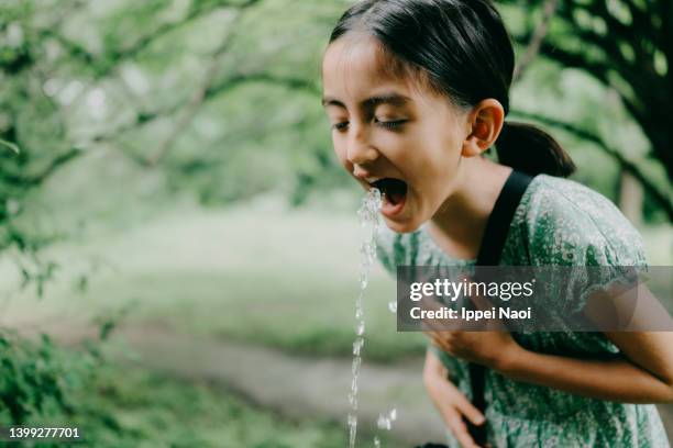 young girl drinking water from public park fountain - drinkwaterfontein stockfoto's en -beelden