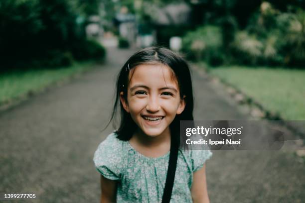 young girl smiling at camera in park - cabelo preto imagens e fotografias de stock