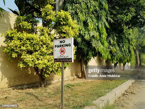 no parking signboard fixed in front of trees in a city street or road. - placa de proibido estacionar imagens e fotografias de stock