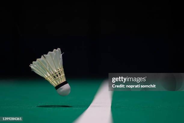 shuttlecock floating on a green badminton court. background, taken in low light. - badminton court stock-fotos und bilder