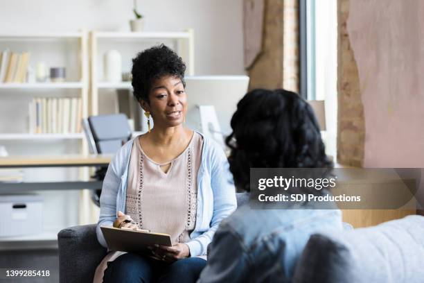 mature female counselor gives unrecognizable young woman advice - therapist imagens e fotografias de stock