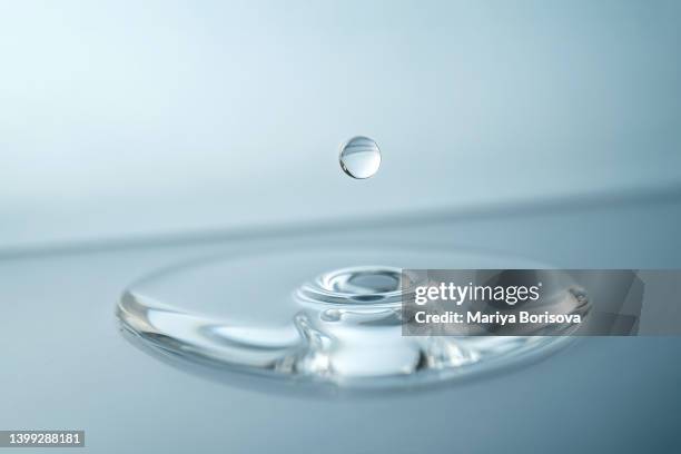 a drop of water, oil, serum or other suitable liquid on a blue background. - ácido hialurónico imagens e fotografias de stock