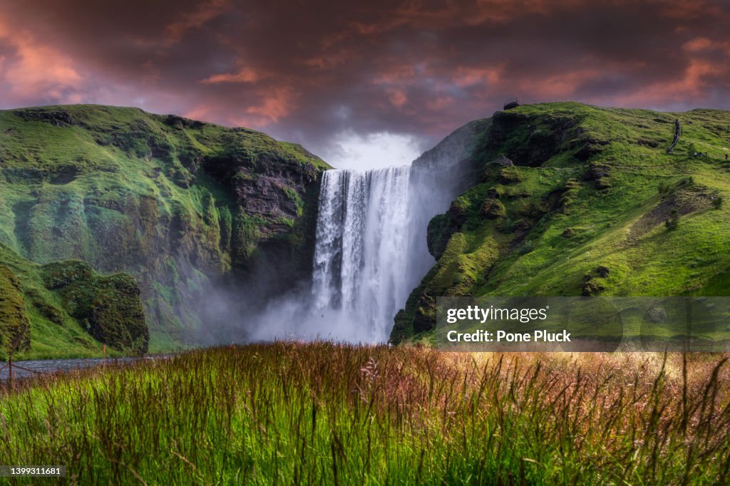 View of famous Skogafoss waterfall with colorful sky during sunset, Iceland