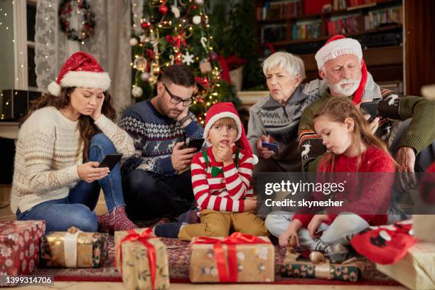 bored extended family using mobile phones on christmas day. - chat noel stockfoto's en -beelden