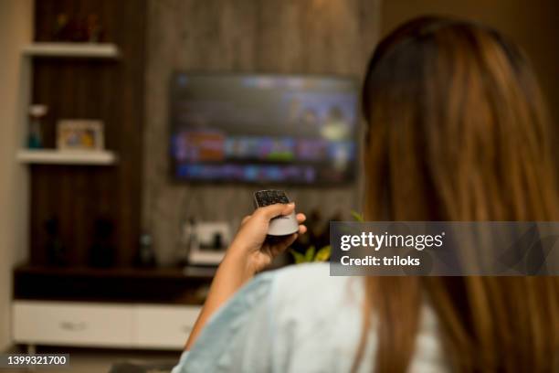 woman watching tv using remote control - smart tv stock pictures, royalty-free photos & images