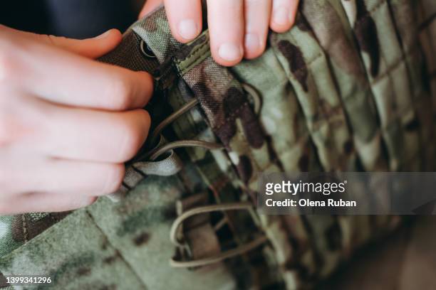 female hands adjusting tactical load bearing vest. - ammunition fotografías e imágenes de stock