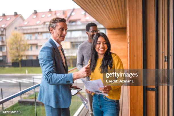 male real estate agent showing the balcony view of a duplex to a young beautiful couple - first girlfriend stock pictures, royalty-free photos & images