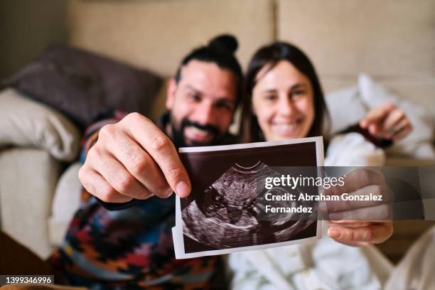 couple sitting on the floor showing ultrasound to camera. - ecografía fotografías e imágenes de stock